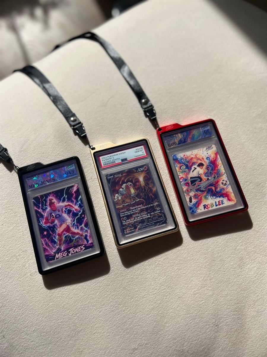 All three lanyard cases on their lanyards: Black, Light Gold and Red, each holding a graded slab